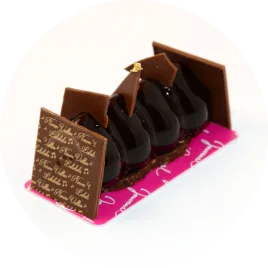 Une présentation élégante du gâteau, avec sa mousse chocolat enrobée d'un croustillant feuilletine, décorée de détails raffinés.